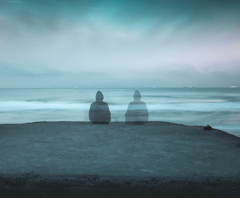 Image of a lonely and isolated person sitting on the beach